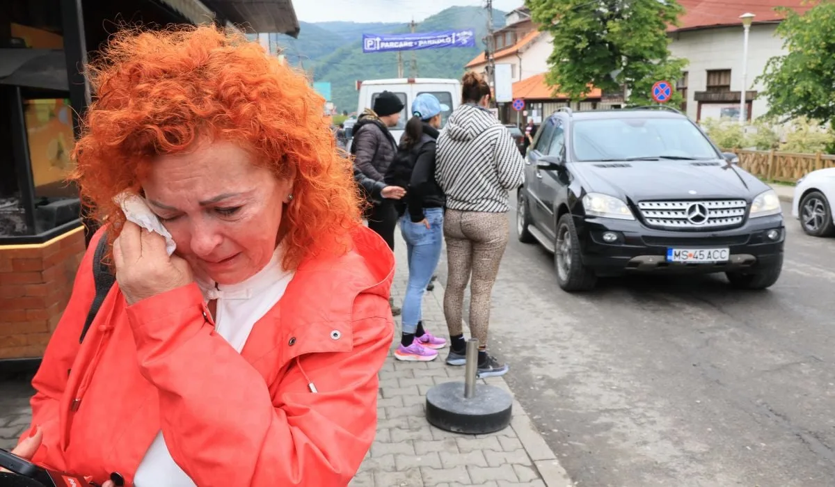 un brabat cu un hanorac gri si mainile ridicate vorbeste unor jurnalisti cu microfoane si camere de filmat, in spatele lui mai multi oameni adunati, o masina si camere pe trepiezi